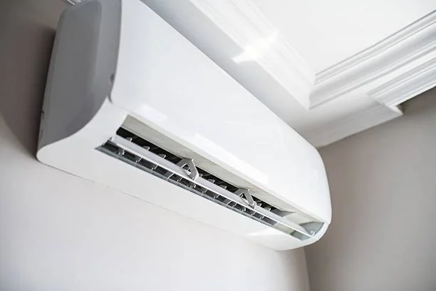 Technician installing a split unit air conditioner on an interior wall